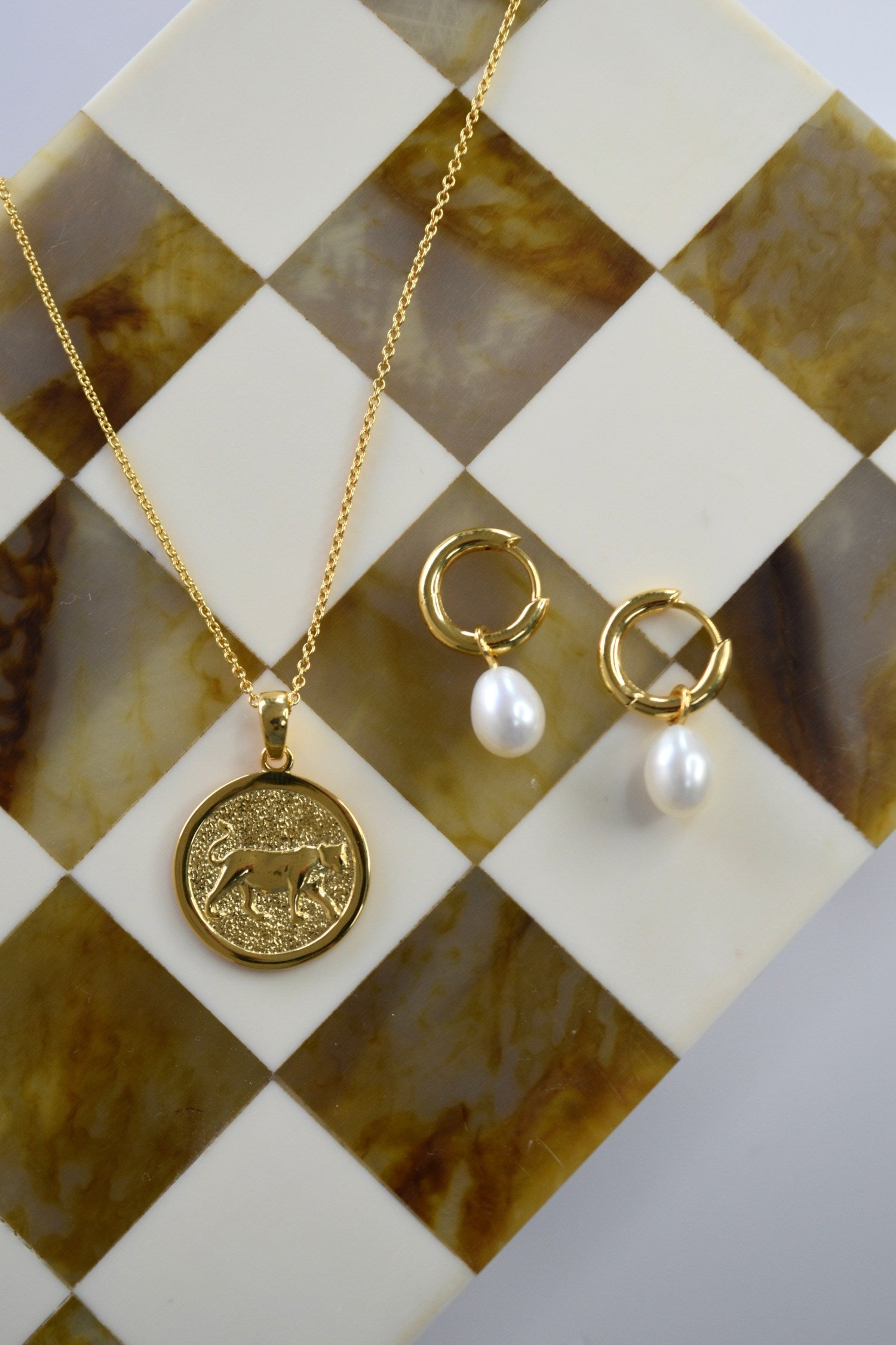 gold lioness pendant and gold drop pearl huggies